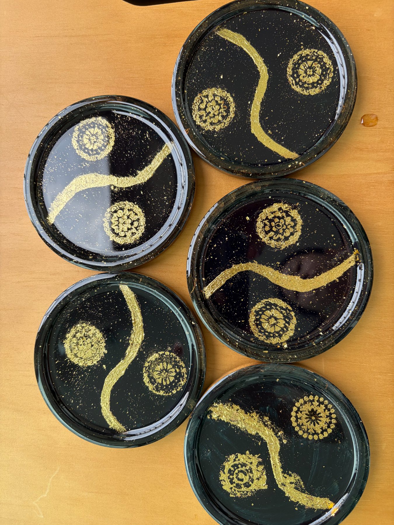 Black coasters with gold-leaf strokes and stamped medallions